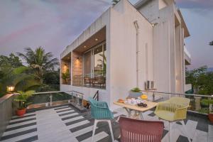 a house with a balcony with a table and chairs at Elegant Villa By Tropicana Stays in Lonavala