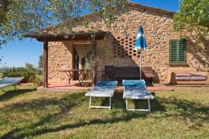 zwei Stühle, einen Tisch und einen Regenschirm in einem Hof in der Unterkunft Agriturismo Pelagaccio in Peccioli