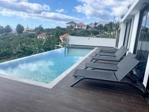 a swimming pool with lounge chairs on a balcony at Villa Sea View in Arco da Calheta