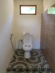 a small bathroom with a toilet with a window at Avocado homestay in Tetebatu