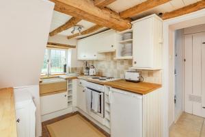 Il comprend une cuisine avec des placards blancs et des plafonds en bois. dans l'établissement Anchor Gate Cottage Near Le Manoir A'QuatSaisons By Aryas Properties - Oxfordshire, à Stadhampton