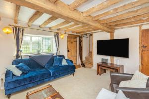 a living room with a blue couch and a flat screen tv at Anchor Gate Cottage Near Le Manoir A'QuatSaisons By Aryas Properties - Oxfordshire in Stadhampton