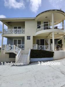 a large white house with three floors and a balcony at Sunset Nook: Cozy one bedroom apartment in Saint James
