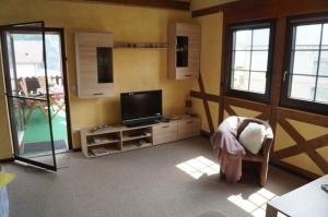 ein Wohnzimmer mit einem Flachbild-TV und einem Stuhl in der Unterkunft Ferienwohnung Weingarten in Piesport