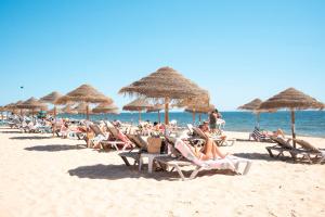 eine Gruppe von Menschen, die am Strand mit Sonnenschirmen sitzen in der Unterkunft Beach Apartment in Faro