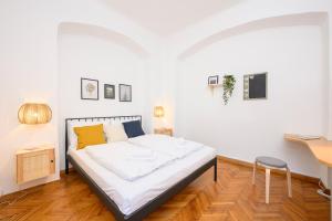 a white bedroom with a bed and a desk at City Center Mödling in Mödling