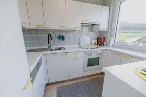 a white kitchen with white cabinets and a window at Ferienhaus Schöne Aussicht Ferienwohnung Gelb in Hemfurth-Edersee +16 photos