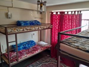 2 łóżka piętrowe w pokoju z czerwonymi zasłonami w obiekcie Backpackers Hub w mieście Dardżyling
