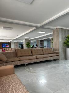 een lobby met bruine leren banken in een gebouw bij Spazzio diRoma Acesso Gratuito ao Aqua Park in Caldas Novas