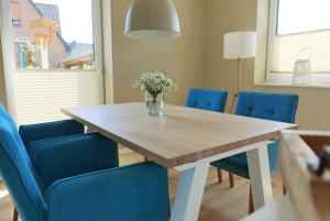 a dining room table with blue chairs and a vase of flowers at Borbyer Perle in Eckernförde