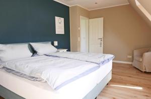 a bedroom with a large white bed with a green wall at Borbyer Perle in Eckernförde