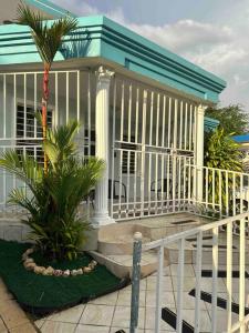a house with a white railing and palm trees at Studio21-B Centric Comfort House in Bayamón