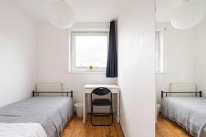 a bedroom with two beds and a desk and a window at Spacious Room with City Skyline Views close to London Eye in London