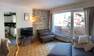 sala de estar con sofá y ventana grande en Best location in Leukerbad!, en Leukerbad