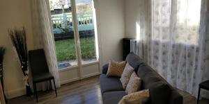 - un salon avec un canapé et 2 fenêtres dans l'établissement Chez Léontine, à Vic-sur-Cère
