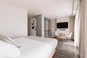 a white bedroom with a bed and a tv at Punta Trouville Hotel in Montevideo