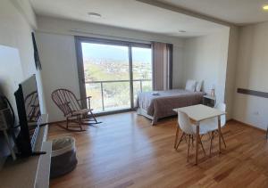 a bedroom with a bed and a table and a window at Apart Hotel Quijote by DOT Suites in Ciudad Lujan de Cuyo