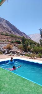 dwoje ludzi pływa w niebieskim basenie w obiekcie Hermosa cabaña para 4 personas con tinaja-Cochiguaz Valle de Elqui w mieście Monte Grande