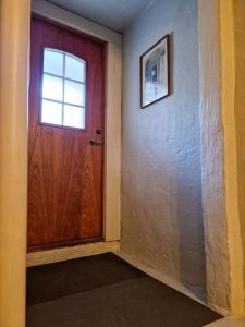 pasillo con puerta de madera y ventana en Koselig kjellerleilighet en Bergen