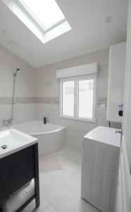 a white bathroom with a tub and a sink at Orly Serenity House Paris 20min Aéroport 12min Parking gratuit in Orly