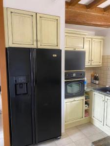 La cuisine est équipée d'un réfrigérateur noir et d'un four micro-ondes. dans l'établissement Le Clos Violet Clessé Holiday Home For 6, à Clessé