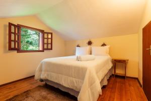 a bedroom with a large white bed with a window at Pousada Serra Villena in Monte Verde +24 photos