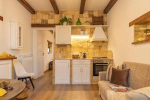 cocina y sala de estar con armarios blancos y sofá en Ginevra Home en Monterosi