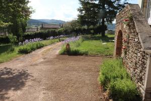 una pared de piedra junto a un camino de tierra con flores en Le Clos De Marie Holiday Home For 4 Berz La Vill, en Berzé-la-Ville