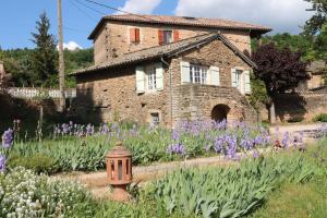 una casa con un jardín con flores púrpuras y una boca de incendios en Le Clos De Marie Holiday Home For 4 Berz La Vill, en Berzé-la-Ville