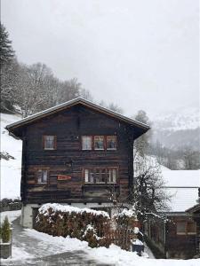 uma casa de madeira com neve no chão em Cosy mountain apartment 5min walk from Gondola em Fiesch
