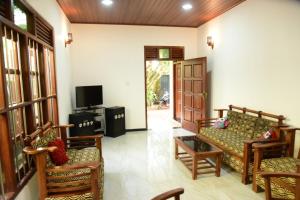 a living room with a couch and a tv at Sanjee Villa Hikkaduwa in Hikkaduwa