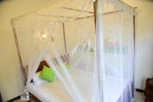 a bedroom with a canopy bed with white curtains at Sanjee Villa Hikkaduwa in Hikkaduwa