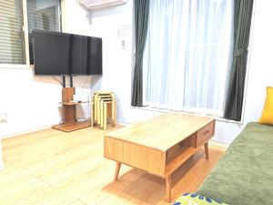 ein Wohnzimmer mit einem TV und einem Couchtisch in der Unterkunft KIK HOUSE-Self Check in- Will send room number and password in Tokio