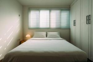- une chambre avec un grand lit blanc et une fenêtre dans l'établissement Leo's house NYC in Daegu, à Daegu