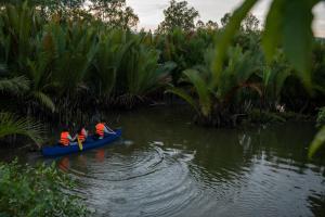 three people in a blue canoe on the water at Kampot Eco Village in Kampot