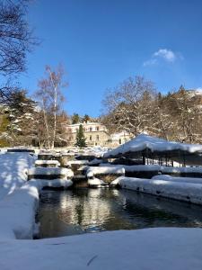 une rivière couverte de neige à côté d'un bâtiment dans l'établissement Château le Beylon - Chambres d'hôtes, à Montmaur