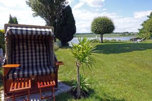 a chair sitting in the grass next to a tree at Fischreiher 2 in Kappeln