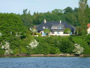 a house on top of a hill next to a lake at Fischreiher 1 in Kappeln