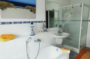 a white bathroom with a shower and a sink at Fischreiher 1 in Kappeln