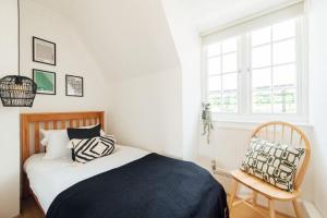 a bedroom with a bed and a chair and a window at Stylish Central Kings Cross 2 Bedroom Flat in London