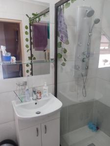 a white bathroom with a shower and a sink at Mosaic Guesthouse Welkom in Welkom
