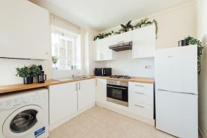 a kitchen with white cabinets and a washer and dryer at Stylish Central Kings Cross 2 Bedroom Flat in London