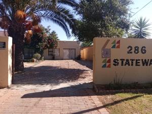 a sign in front of a building with a driveway at Mosaic Guesthouse Welkom in Welkom