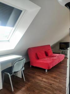 a red couch in the corner of a room with a desk at das Apartmenthaus in Freiburg in Freiburg im Breisgau