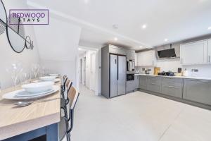 a kitchen with a long table and chairs in a room at HUGE 5 Bed 3 Bath House For Contractors & Families, X2 FREE PARKING, FREE WiFi & Netflix By REDWOOD STAYS in Farnborough