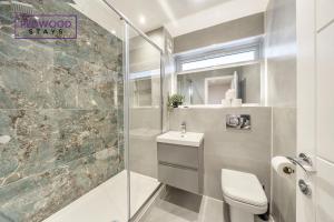 uma casa de banho com um chuveiro, um WC e um lavatório. em HUGE 5 Bed 3 Bath House For Contractors & Families, X2 FREE PARKING, FREE WiFi & Netflix By REDWOOD STAYS em Farnborough