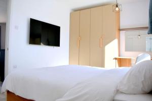 um quarto com uma cama branca e uma televisão de ecrã plano em Seaside Serenity Retreat em St. Paul's Bay