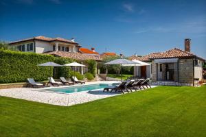 a yard with a swimming pool with chairs and umbrellas at Rustic villa Inga with pool and grill in Buje in Kaštel