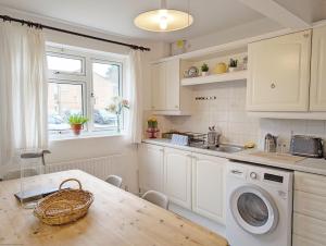 a kitchen with a table and a washing machine at Holly House - Rustington in Rustington