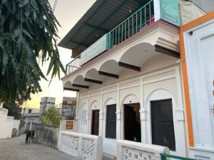 a white building with a balcony on top of it at Kalakriti Homestay in Rishīkesh